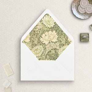 May include: A white envelope with a floral patterned interior. The pattern features cream and green flowers and foliage. The envelope is open, revealing the design. Stamps, a ring box, and decorative wax seals are also visible.