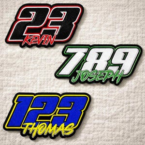 May include: Three embroidered patches with racing-style numbers and names. The top patch features the number 23 with the name "KEVIN" in red. The middle patch has the number 789 with "JOSEPH" in green. The bottom patch displays 123 and "THOMAS" in yellow.