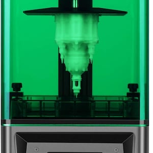 Puede incluir: Una impresora 3D con una cubierta verde transparente y una base negra. La impresora tiene una pantalla digital con iconos para herramientas, sistema y funciones de impresión. Se muestra la marca "ELEGOO" y el modelo "MARS 2".