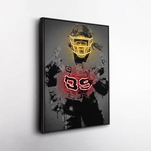 May include: Framed artwork depicting a football player in a neon-style illustration. The player wears a helmet and jersey with the number 99 in red neon. The artwork has a dark, grunge-style background.