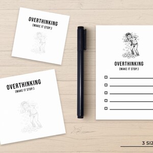 May include: A black pen rests beside three white notepads with the text "OVERTHINKING (MAKE IT STOP.)". One notepad has a checklist. The notepads feature a cartoon illustration of a person surrounded by thoughts.