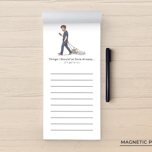 May include: A white magnetic notepad with a black pen, featuring an illustration of a person walking while pulling a pile of items on a leash. The text reads: Things I Should've Done Already... (I'll get to it.) The pad has ten horizontal lines for writing.