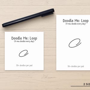 May include: Two white paper pads with black text reading Doodle Me: Loop (A new doodle every day) and 30+ doodles per pad, featuring a simple black loop drawing on each, accompanied by a black felt-tip pen positioned above the two rectangular pads.