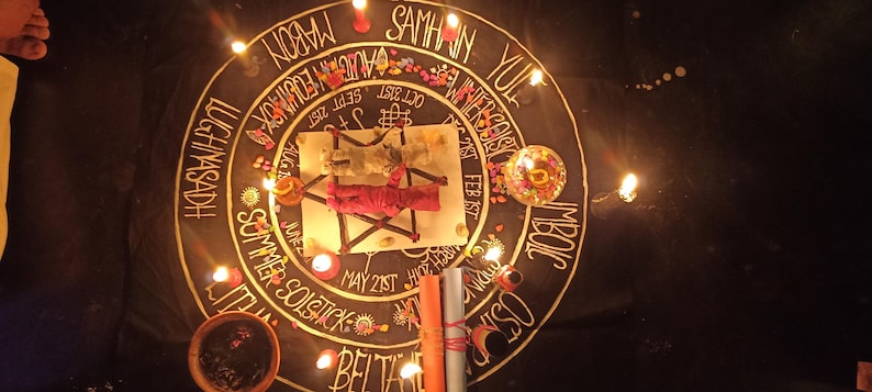 K&ouml;nnte beinhalten: Ein Ritualaltar auf schwarzem Tuch, mit einem zentralen wei&szlig;en Quadrat, das ein rot umwickeltes Objekt enth&auml;lt. Ein Kreis mit Text und Kerzen umgibt das Quadrat. Zus&auml;tzliche Kerzen, eine Schale und gerollte Gegenst&auml;nde sind ebenfalls vorhanden. Die Szene wird von Kerzenlicht beleuchtet.