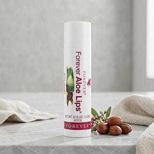 May include: A white tube of Forever Aloe Lips lip balm with a botanical illustration and the text "Forever Aloe Lips". The product is accompanied by shea nuts and a sprig of leaves. Net wt. 0.15 oz.