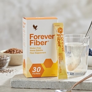 Może przedstawiać: Pudełko suplementu diety Forever Fiber, saszetka i szklanka wody. Pudełko jest biało-pomarańczowe z napisami "Forever Fiber" i "Suplement błonnika rozpuszczalnego w wodzie bez glutenu". Saszetka jest żółto-pomarańczowa.