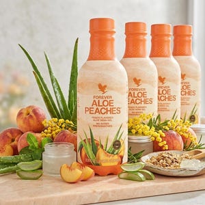 以下が含まれることがあります： Forever Aloe Peachesの4本のボトル、ピーチ風味のアロエベラジェルが、新鮮な桃、アロエベラ葉、黄色の花とともに展示されています。ボトルはオレンジ色のキャップと、製品名とロゴが記載されたラベルが付いています。
