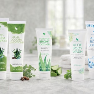 May include: A selection of Forever Living aloe vera products, including shampoo, conditioner, toothpaste, body wash, and body lotion. The tubes are white with green accents and feature aloe vera illustrations. The shampoo and conditioner are 296 ml.