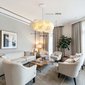 May include: A cloud-shaped pendant light fixture, 50cm x 26cm, hangs from the ceiling. The light is white and emits a soft glow. The fixture hangs 200cm from the ceiling. The room features a sofa, chairs, and a coffee table.