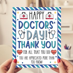 Puede incluir: Una tarjeta de felicitación con el texto "HAPPY DOCTORS DAY! THANK YOU" en azul y blanco. La tarjeta presenta símbolos médicos y un borde a rayas. La tarjeta está sostenida por una persona.