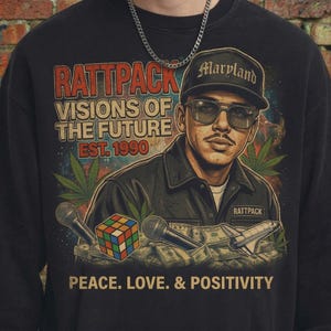 Puede incluir: Sudadera negra con un gráfico que presenta a un hombre con una gorra "Maryland" y gafas de sol. El diseño incluye el texto "Rattpack Visions of the Future Est. 1990" y las palabras "Peace. Love. & Positivity."