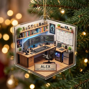 May include: A clear, square-shaped acrylic ornament featuring a miniature 3D office scene with a desk, computer monitors, keyboard, chair, and shelves. A nameplate at the bottom reads ALEX SOFTWARE DEVELOPER in black text on a tan background.