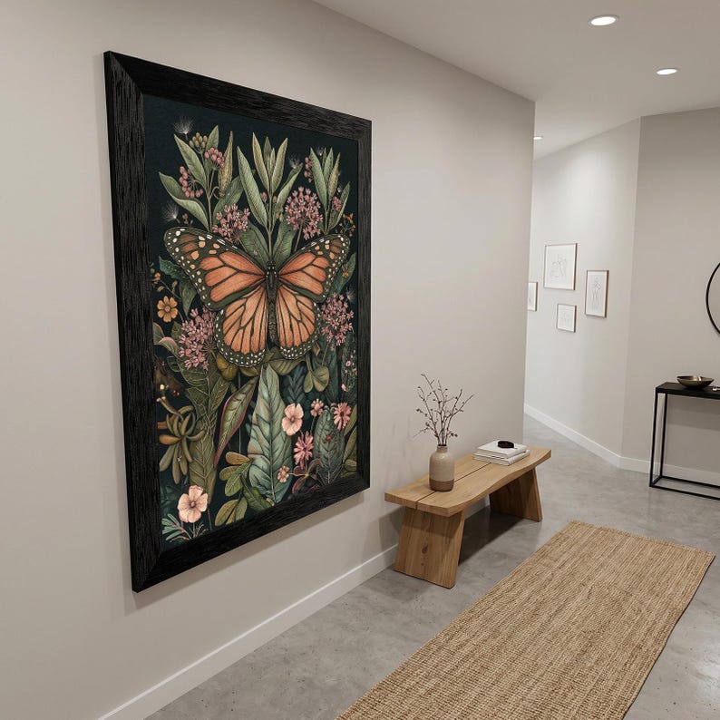 May include: A framed art print featuring a monarch butterfly with orange and black wings, surrounded by detailed botanical illustrations in shades of green, pink, and cream. The artwork is set against a dark background and framed in black.
