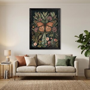 May include: Framed artwork featuring a monarch butterfly with orange and black wings, surrounded by green leaves and pink flowers. The artwork is set against a dark background and framed in black. The overall theme is nature and botanical.