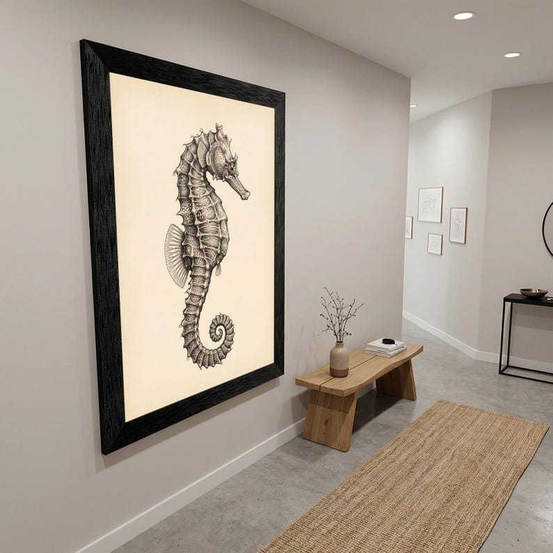 May include: A framed black and white seahorse art print. The seahorse is detailed with shading and texture, set against a cream-colored background. The frame is a thick, dark wood, adding a classic touch to the artwork.