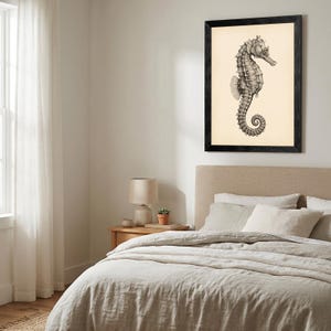 May include: Black framed print featuring a detailed grayscale illustration of a seahorse. The seahorse is depicted in a side profile against a cream-colored background. The artwork is displayed above a bed with neutral-toned bedding.