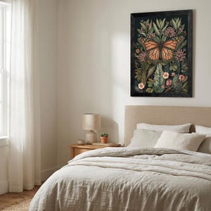 May include: A framed botanical print featuring a monarch butterfly with orange and black wings, surrounded by green leaves and pink flowers. The artwork is set against a dark background and framed in black, adding a touch of nature-inspired decor.
