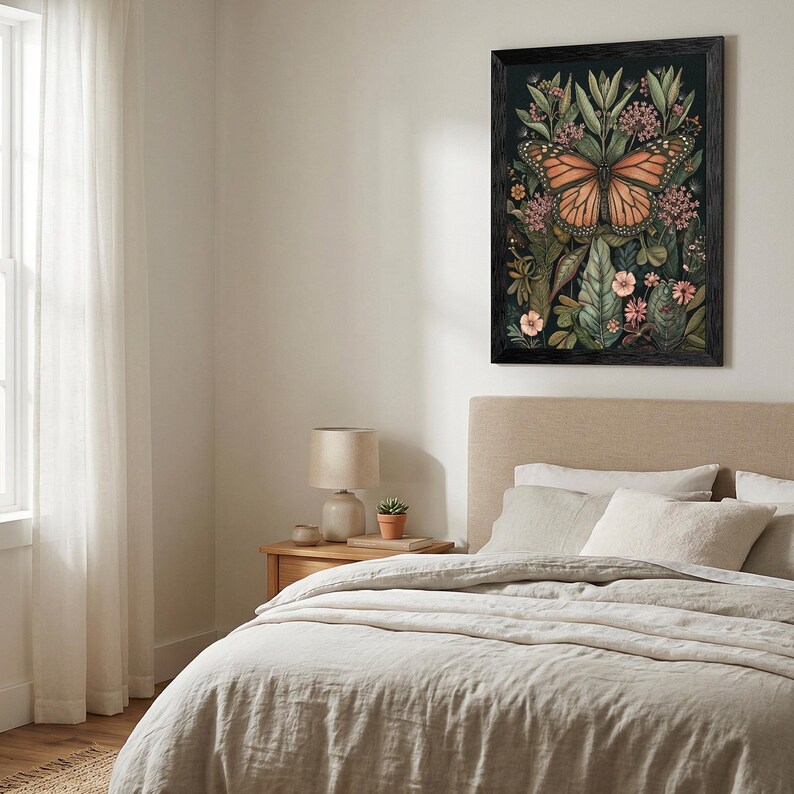 May include: A framed botanical print featuring a monarch butterfly with orange and black wings, surrounded by green leaves and pink flowers. The artwork is set against a dark background and framed in black, adding a touch of nature-inspired decor.