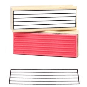 Op de afbeelding: Een houten stempel met een rood rubberen pad. De stempel heeft vijf horizontale lijnen. De stempel wordt gebruikt om een ​​lijnenpatroon te maken.