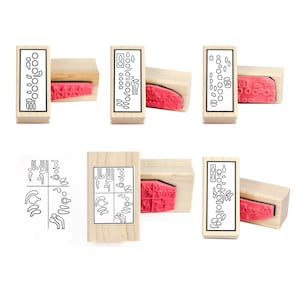 May include: Six wooden stamps with different designs. The stamps are rectangular and have a red ink pad on the bottom. The designs include a series of circles, a series of lines, and a series of symbols. The stamps are ideal for adding a unique touch to your crafts and projects.