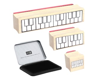 May include: Three wooden stamps with a piano keyboard design. The stamps are different sizes and are arranged in a row from largest to smallest. The stamps are on a white background. The largest stamp has a red top.