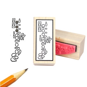 May include: A wooden stamp with a black and white illustration of a stylized human spine. The stamp is mounted on a wooden block with a red rubber stamp on the bottom.