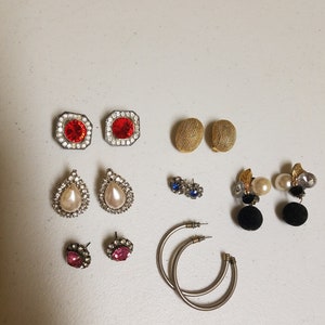 May include: Assortment of earrings in various styles and colors, including red, pink, blue, and white. Some earrings feature pearl accents, while others have geometric designs.