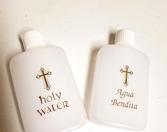 May include: Two white plastic bottles with gold crosses and text. The bottle on the left says "holy water" and the bottle on the right says "Agua Bendita".