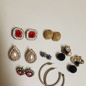 May include: Assortment of vintage earrings in various styles and colors, including red, white, blue, and black. The earrings feature different shapes, such as teardrop, round, and hoop.