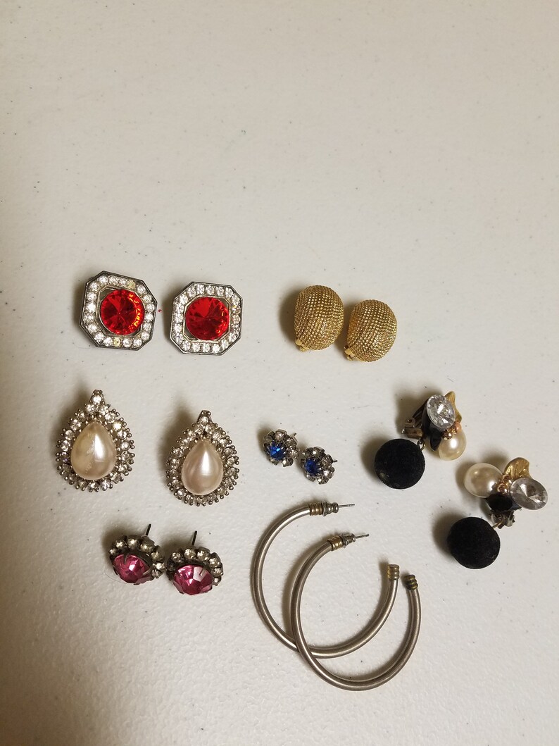 May include: Assortment of vintage earrings in various styles and colors, including red, white, blue, and black. The earrings feature different shapes, such as teardrop, round, and hoop.