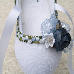 May include: White satin ballet slipper with blue and green embroidered flowers and a blue lace bow.
