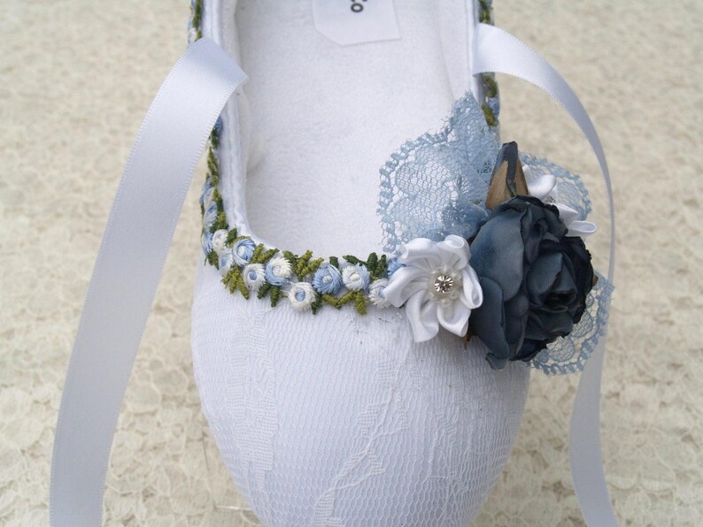 May include: White satin ballet slipper with blue and green embroidered flowers and a blue lace bow.