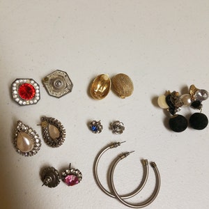 May include: Assortment of earrings in various styles and colors, including silver, gold, and black. Some earrings feature rhinestones, pearls, and other decorative elements.