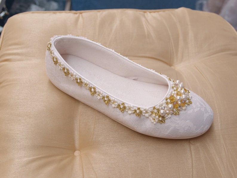 May include: White satin bridal shoes with a pearl and gold bead embellishment.