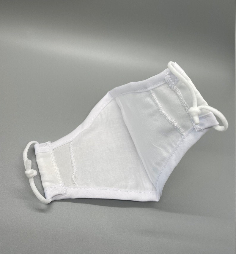 May include: White face mask with adjustable ear loops. The mask is made of a lightweight fabric and features a contoured design for a comfortable fit. The mask is designed to cover the nose and mouth.