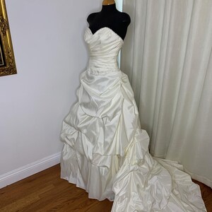 May include: A white strapless wedding dress with a full skirt and a long train. The dress is made of a satin-like fabric and has a fitted bodice.