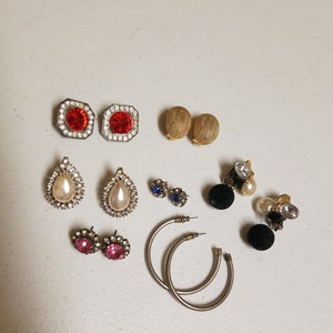 May include: Assortment of vintage earrings in various styles and colors, including red, blue, pink, white, and gold. The earrings feature different shapes, such as teardrop, round, and square.
