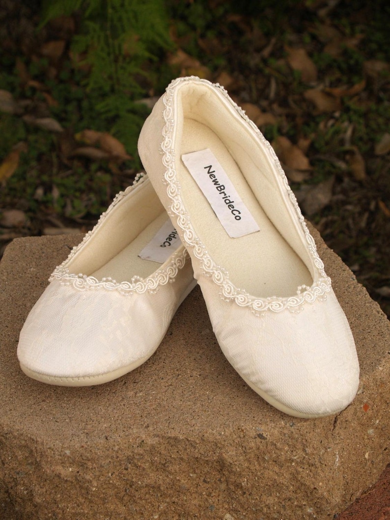 May include: A pair of white satin bridal slippers with a beaded trim and a label that reads "NewBrideCo."