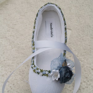 May include: White satin bridal shoes with blue and green embroidery, a blue satin flower, and a white satin ribbon. The shoes have the text "NewBrideCo" printed on the inside.
