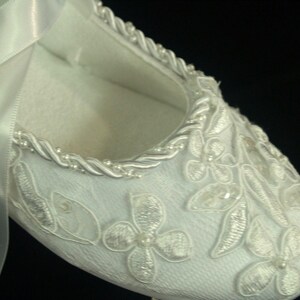 May include: White satin bridal shoe with delicate floral embroidery and a satin ribbon.