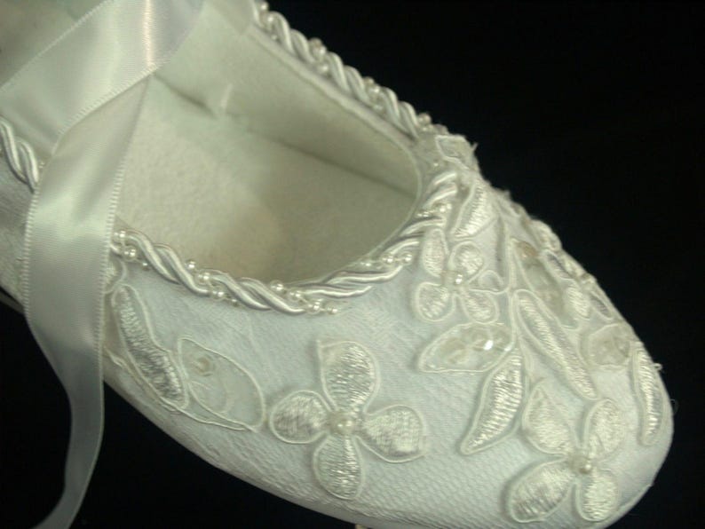 May include: White satin bridal shoe with delicate floral embroidery and a satin ribbon.
