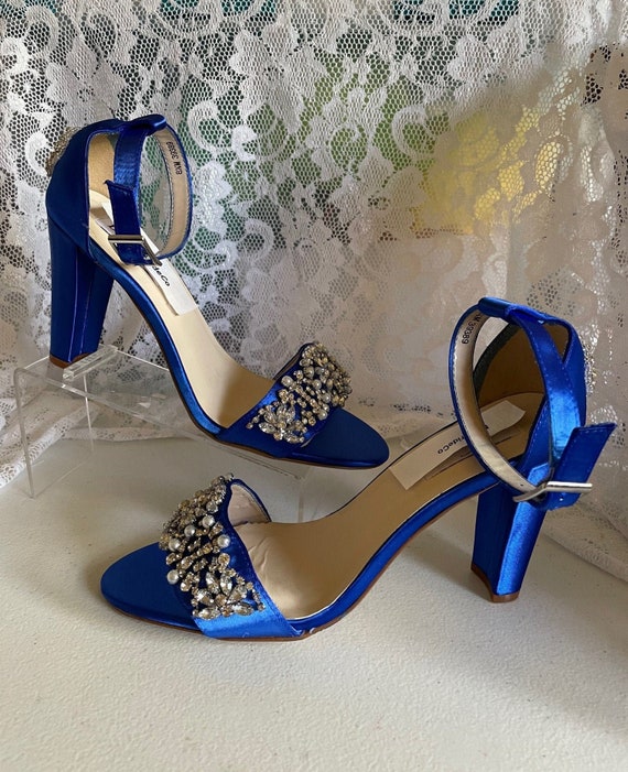 pair of pointed high heels in electric blue colour with a gold crest on  toes and heel covered in black and blue gems