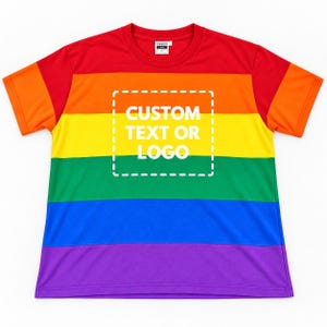 Op de afbeelding: Een T-shirt met korte mouwen en een ronde hals met horizontale strepen in rood, oranje, geel, groen, blauw en paars. In het midden van de borst staat een wit vierkant kader met stippellijn en de tekst CUSTOM TEXT OR LOGO in het wit.