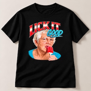 Pode incluir: Uma t-shirt preta de manga curta com uma estampa gráfica de uma pessoa idosa com cabelo branco e óculos a lamber um gelado vermelho. Acima da pessoa, o texto LICK IT GOOD está impresso em letras vermelhas e azuis com contorno branco.