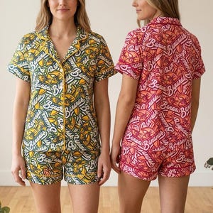 Pu&ograve; includere: Due completi di pigiami a maniche corte. Uno &egrave; giallo con un motivo a banana e testo, l'altro &egrave; rosso con un motivo simile. Entrambi i completi hanno una camicia con colletto e pantaloncini.