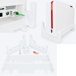 Könnte beinhalten: Eine weiße Wandhalterung aus Kunststoff für einen Router, bestehend aus einem vertikalen Ständer, zwei Seitenstützen und Montagematerial inklusive Schrauben und Dübeln. Der Router ist weiß mit einem roten vertikalen Streifen und einem blauen USB-Anschluss.