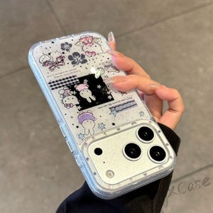 Może przedstawiać: Przezroczyste etui na telefon z błyszczącą obw&oacute;dką i kolorowym wzorem z postaciami z kresk&oacute;wek, kwiatami i gwiazdami. Etui ma prostokątny kształt z trzema obiektywami aparatu.