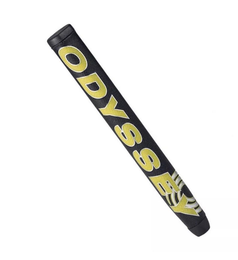 K&ouml;nnte beinhalten: Schwarzer Golfschl&auml;gergriff mit dem Wort "ODYSSEY" in gro&szlig;en gelben Buchstaben. Der Griff hat auch ein gelb-wei&szlig;es Design am unteren Ende. Der Griff ist f&uuml;r einen komfortablen und sicheren Halt f&uuml;r Golfer konzipiert, ca. 27 cm lang.