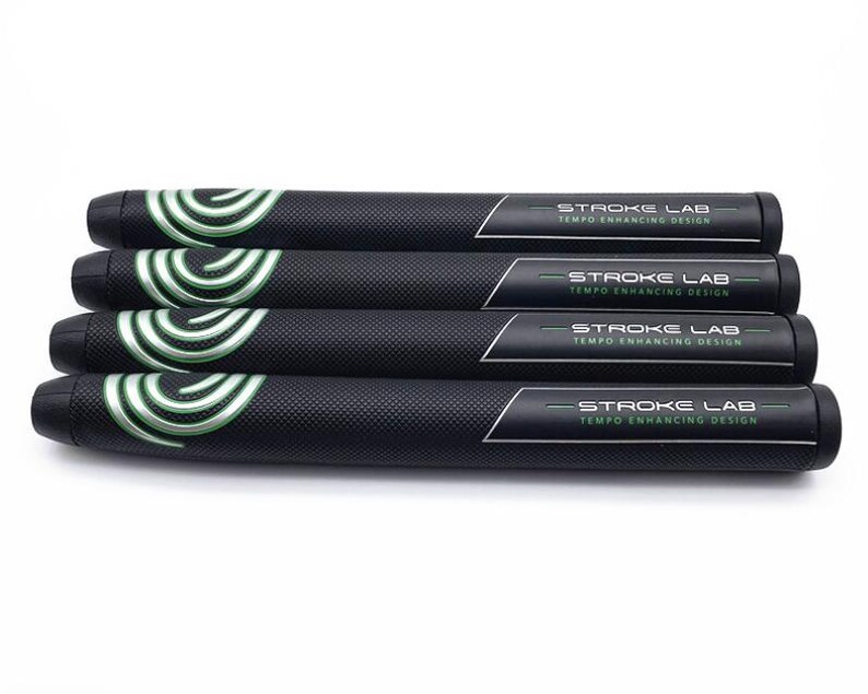 May include: Four black golf club grips with a textured surface. Each grip has a white and green swirl design on one end and the text "STROKE LAB TEMPO ENHANCING DESIGN" on the other end.