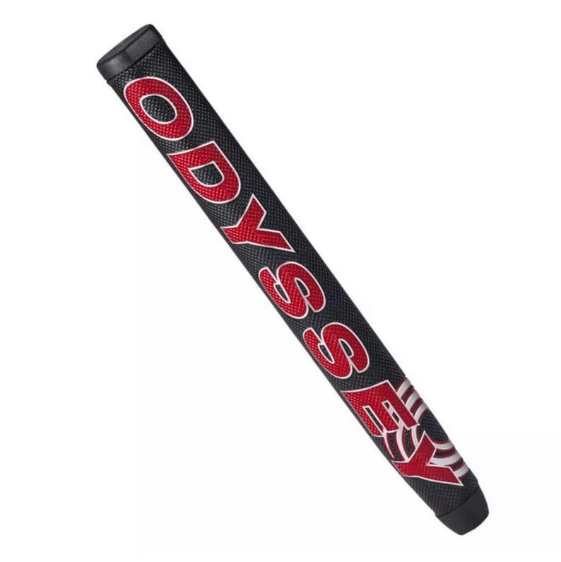 Op de afbeelding: Zwarte golfclubgrip met het woord "ODYSSEY" in rode blokletters. De grip heeft een gestructureerd oppervlak en een zwarte eindkap. Het woord "ODYSSEY" is wit omlijnd.